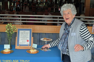 A woman smiling and cutting a cake