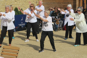 A group of older adults are doing tai chi outside.