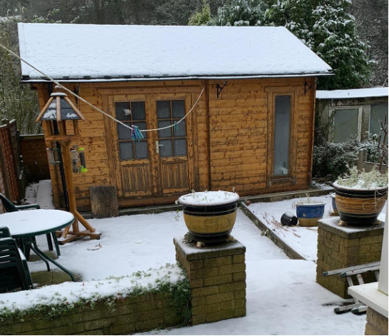 a wooden cabin with snow in a snowy garden