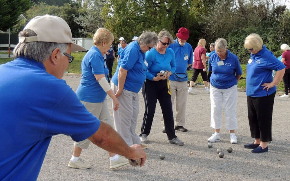 Six U3A members in blue shirts play pétanque 
