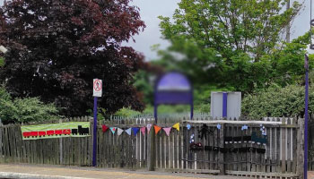 knitted trains and bunting on a fence at a station