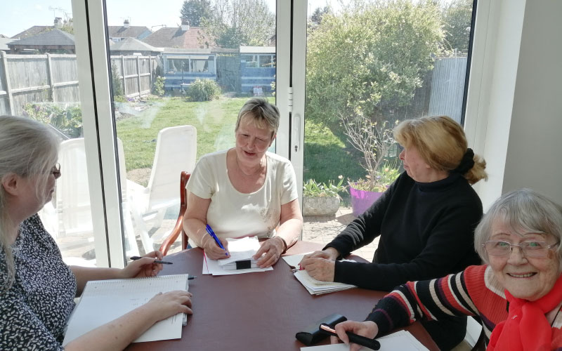Four women sitting around a table writing in notebooks