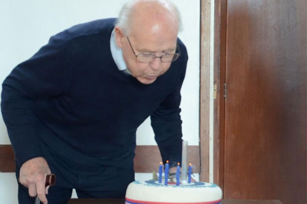 A man is blowing out candles on a birthday cake