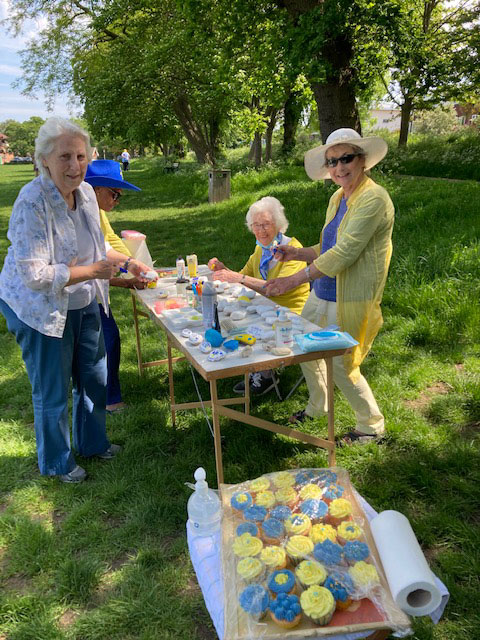 women smiling at the camera as they paint pebbles at a table
