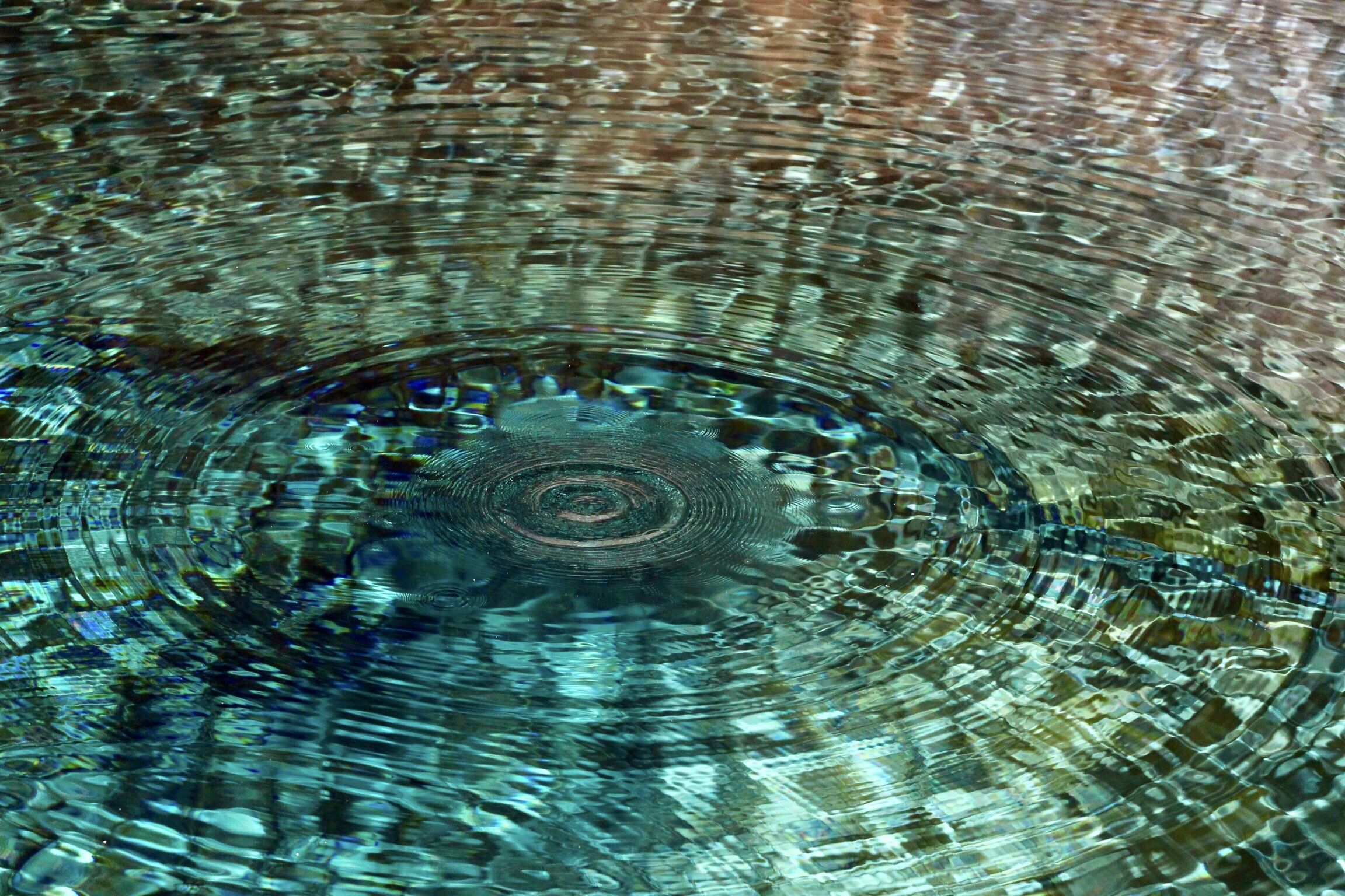 A zoom in photo of a ripple in the sea, the sea is turquoise and clear.