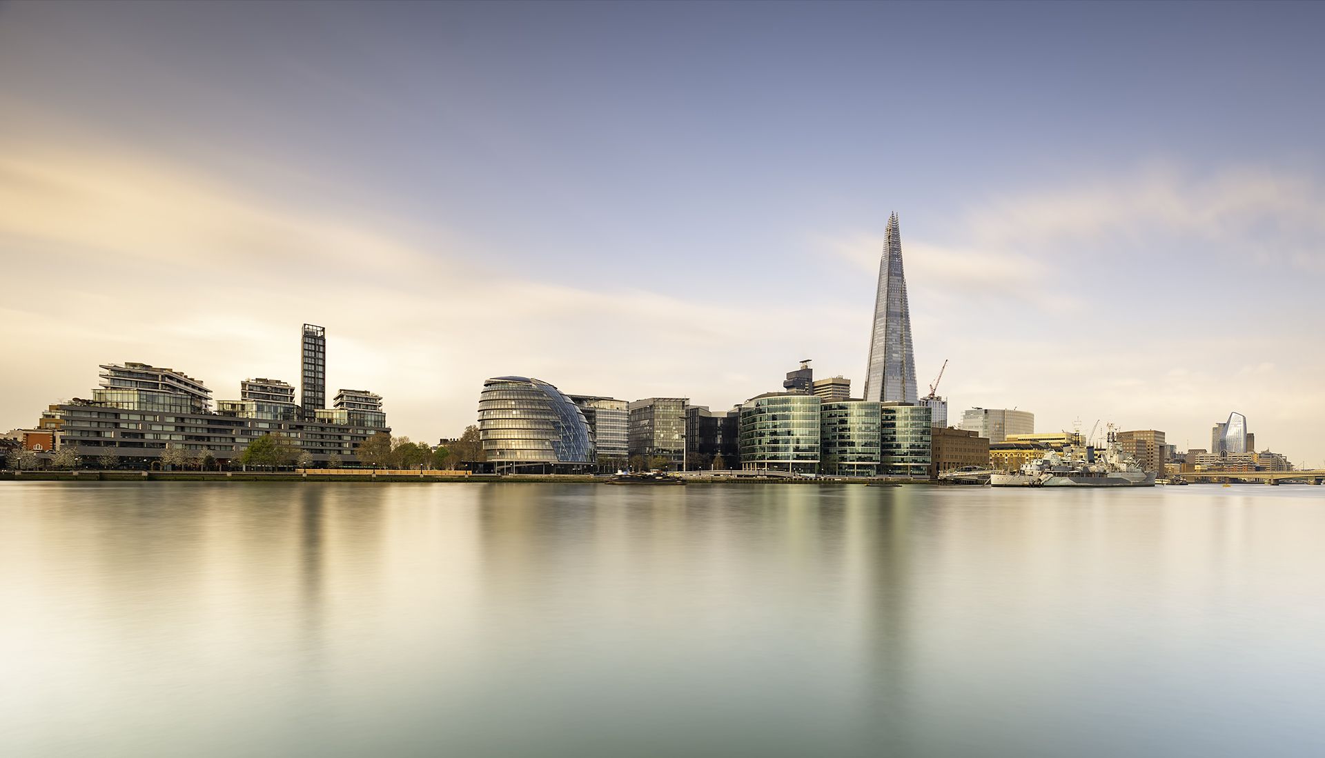 buildings across a river with blue hazy sky in the background