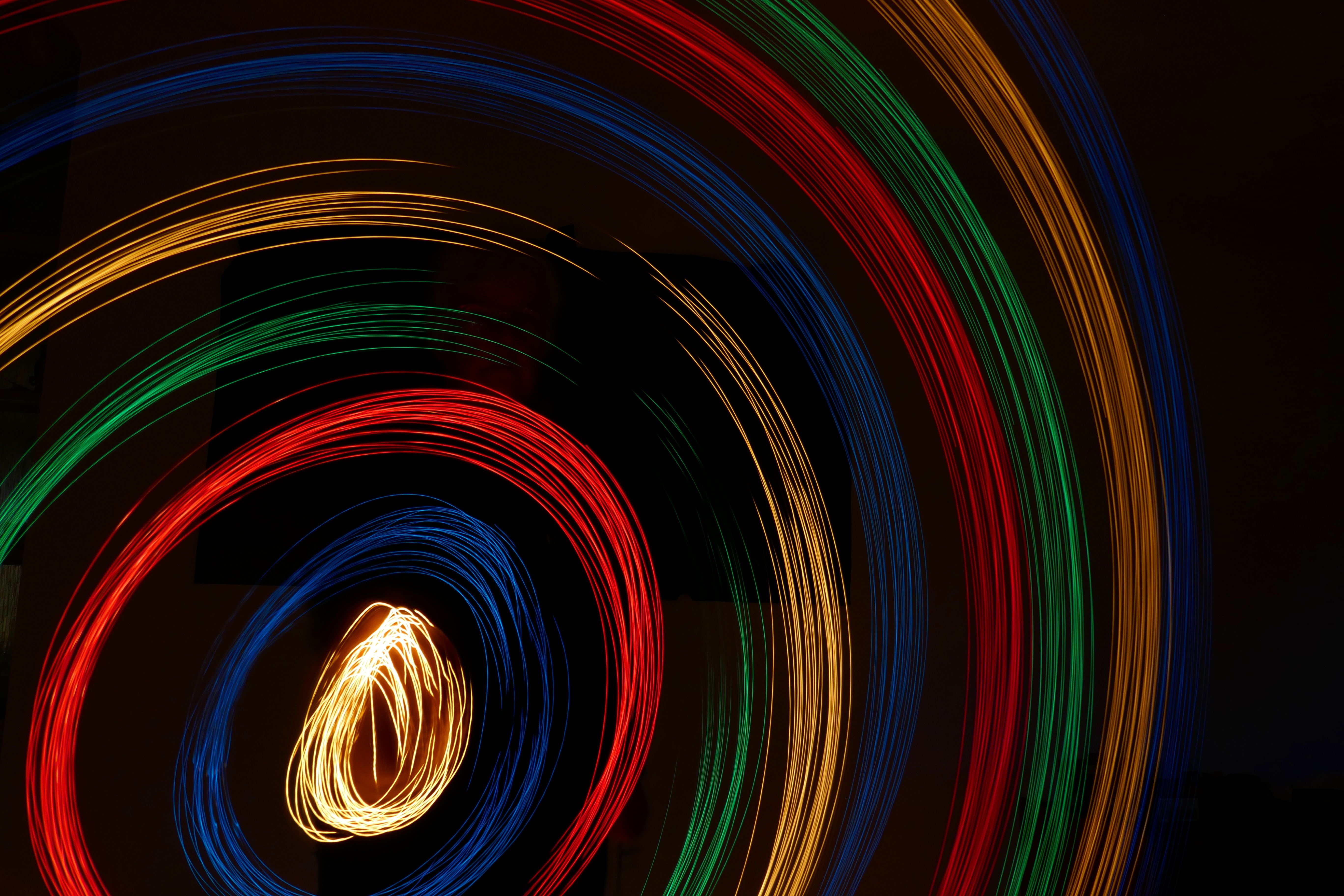 a black background with swirls of light. each line of the swirl is a different colour. From the middle out the lines are yellow, blue, red green repeated twice.