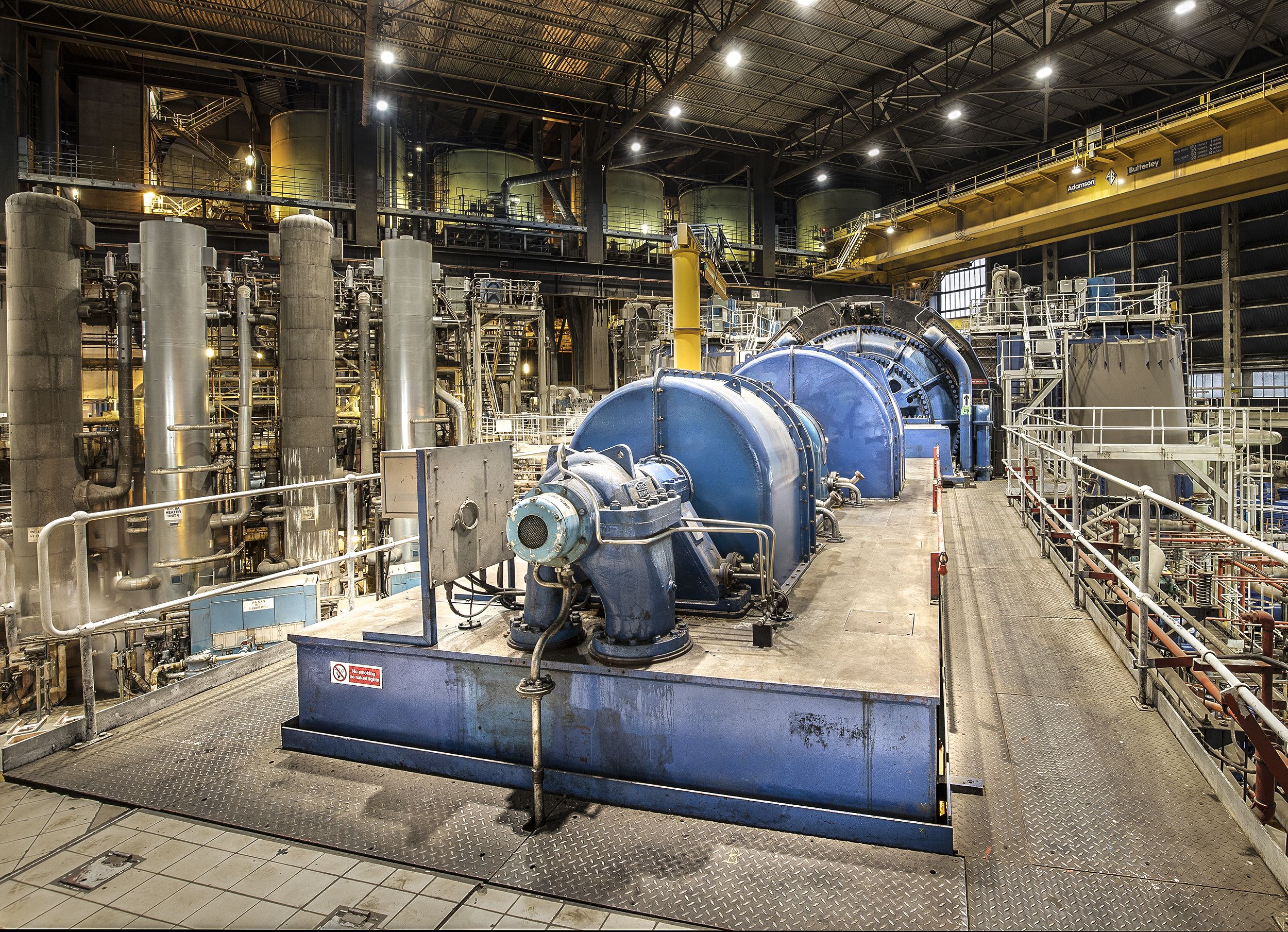 the insides of a power station, with big blue vats and pipes everywhere 