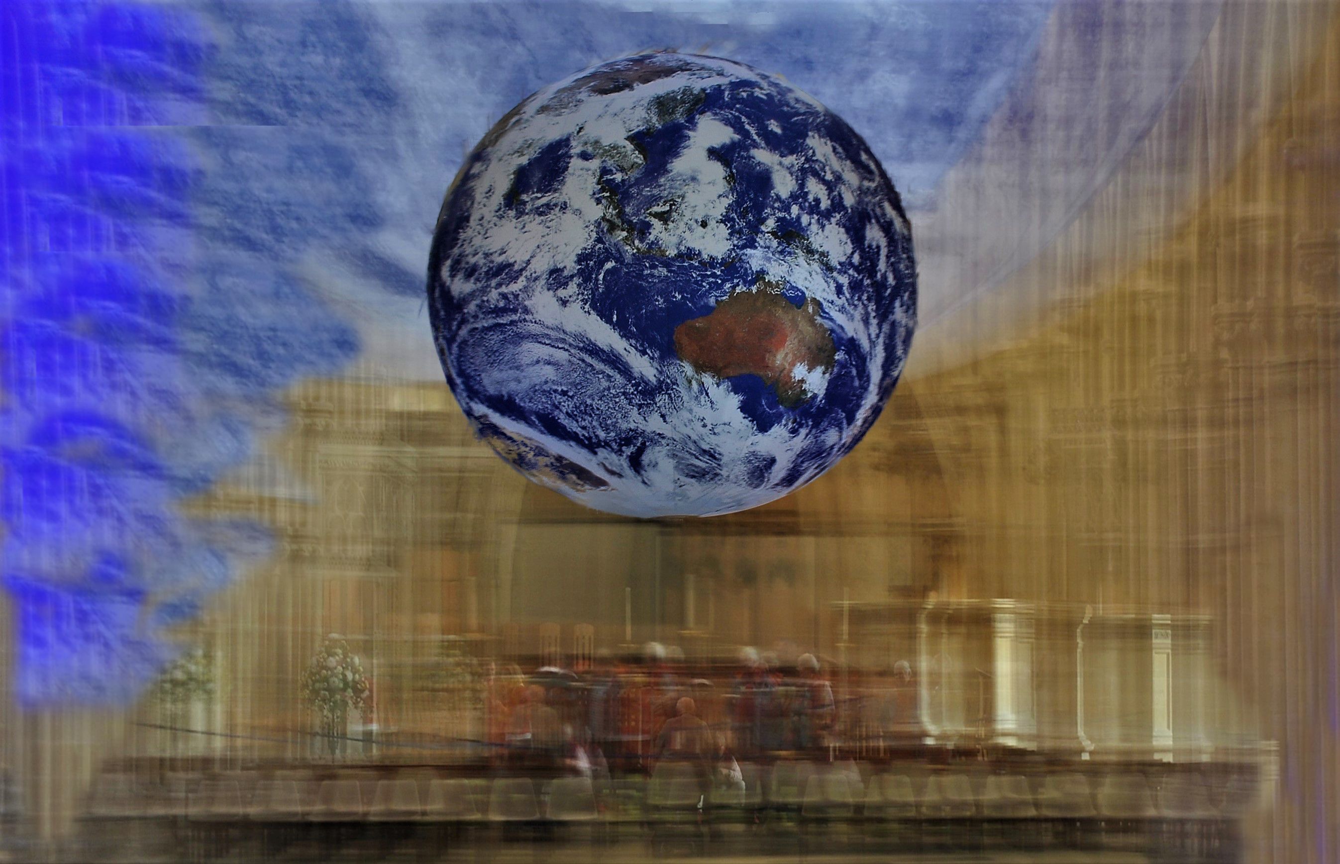 A large globe suspended in the air. The background of the inside of a cathedral is blurred due to the long exposure of the photo. 