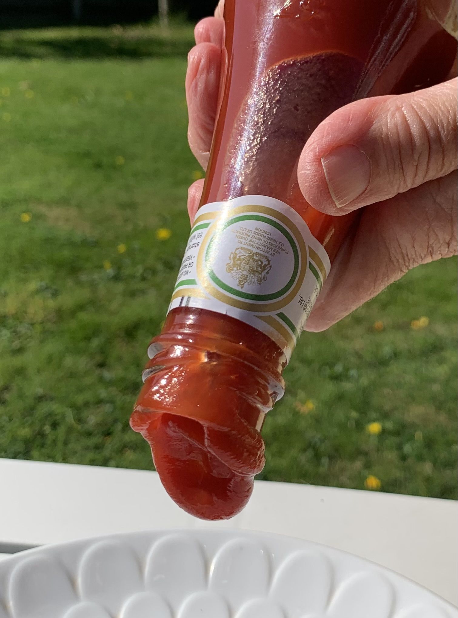 a glass bottle of ketchup upside down, the ketchup waiting to 