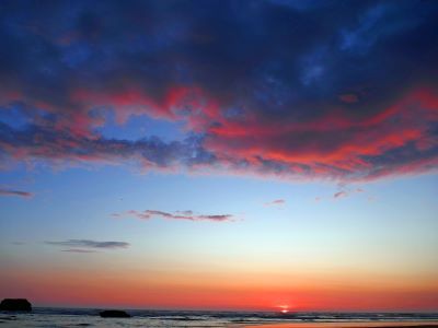 a sunset over the sea with orange sky at the bottom, and red clouds at the top