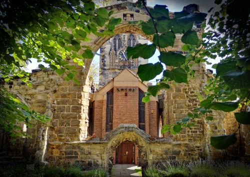 the view of a church through a stone arch with trees surrounding