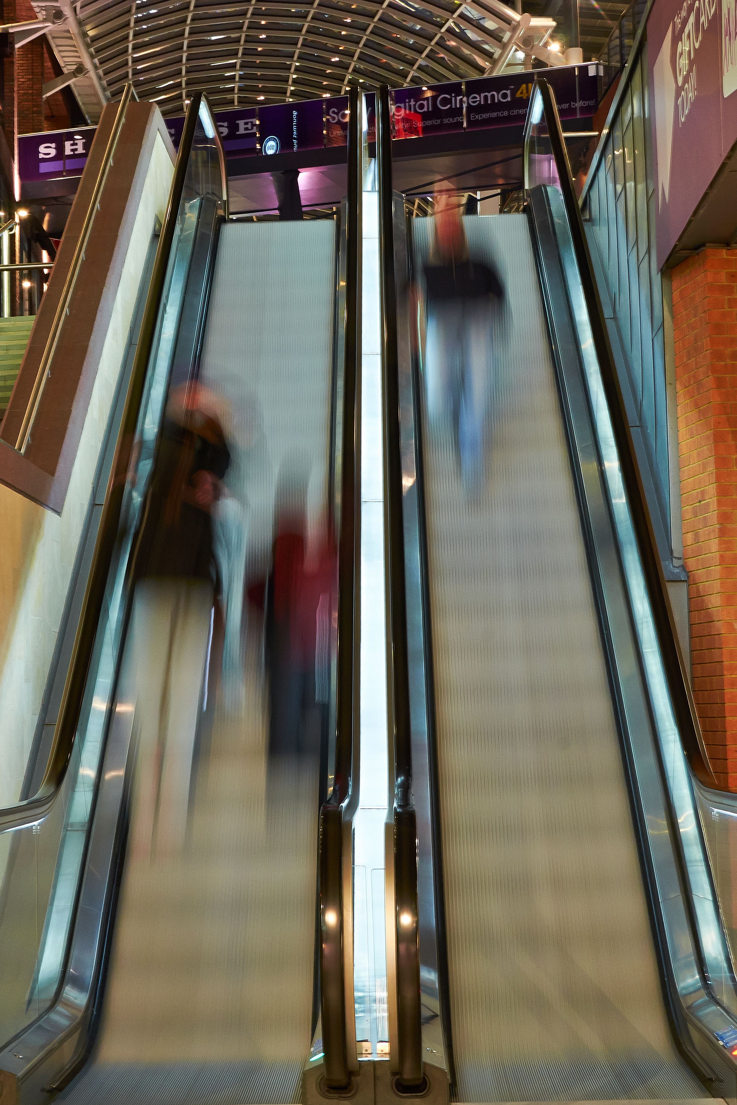 A long exposure shot of two escalators, one going up and one going down. the photo is blurry to show movement. 