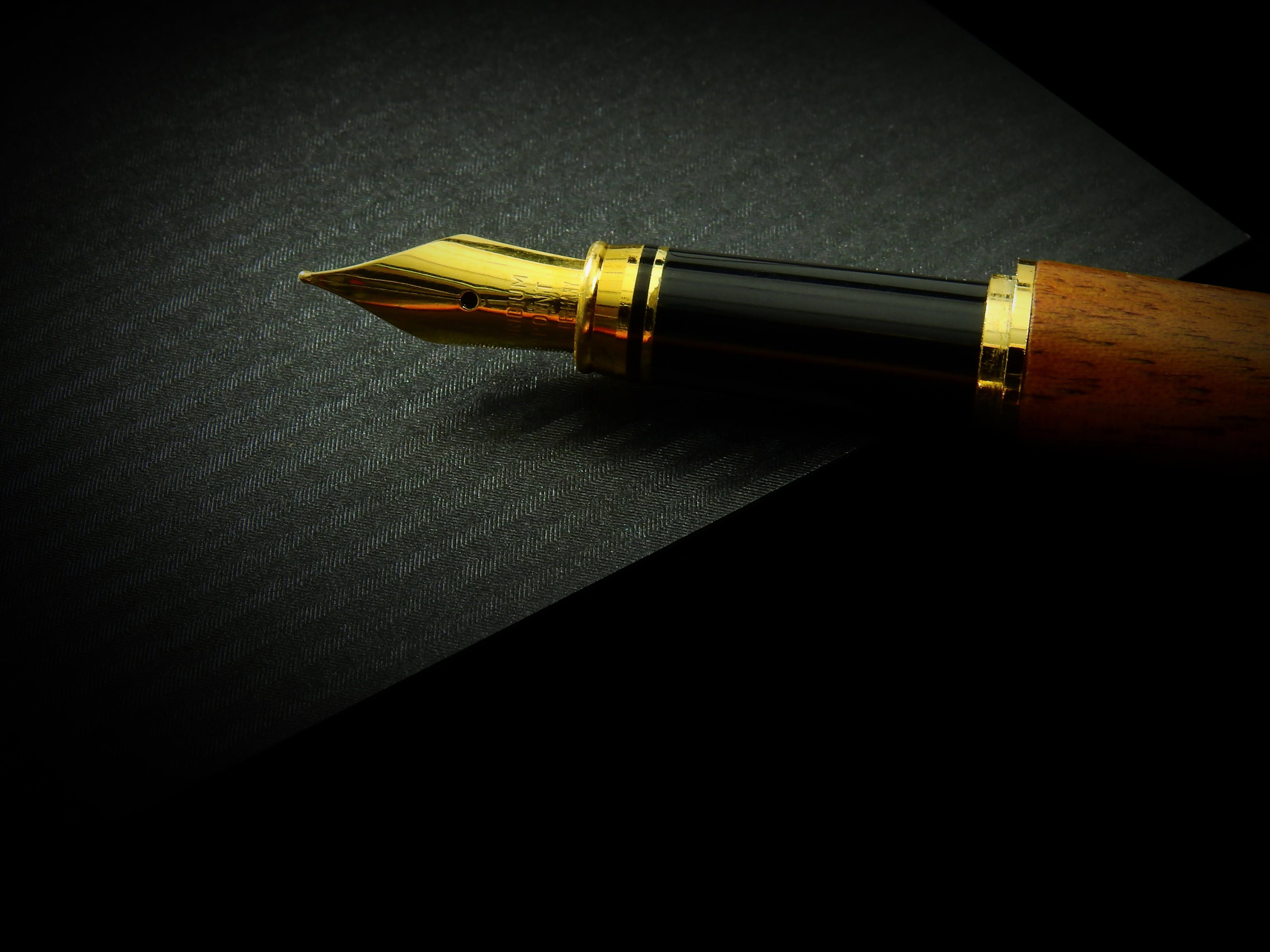 the gold nib of a fountain pen writing on lined paper